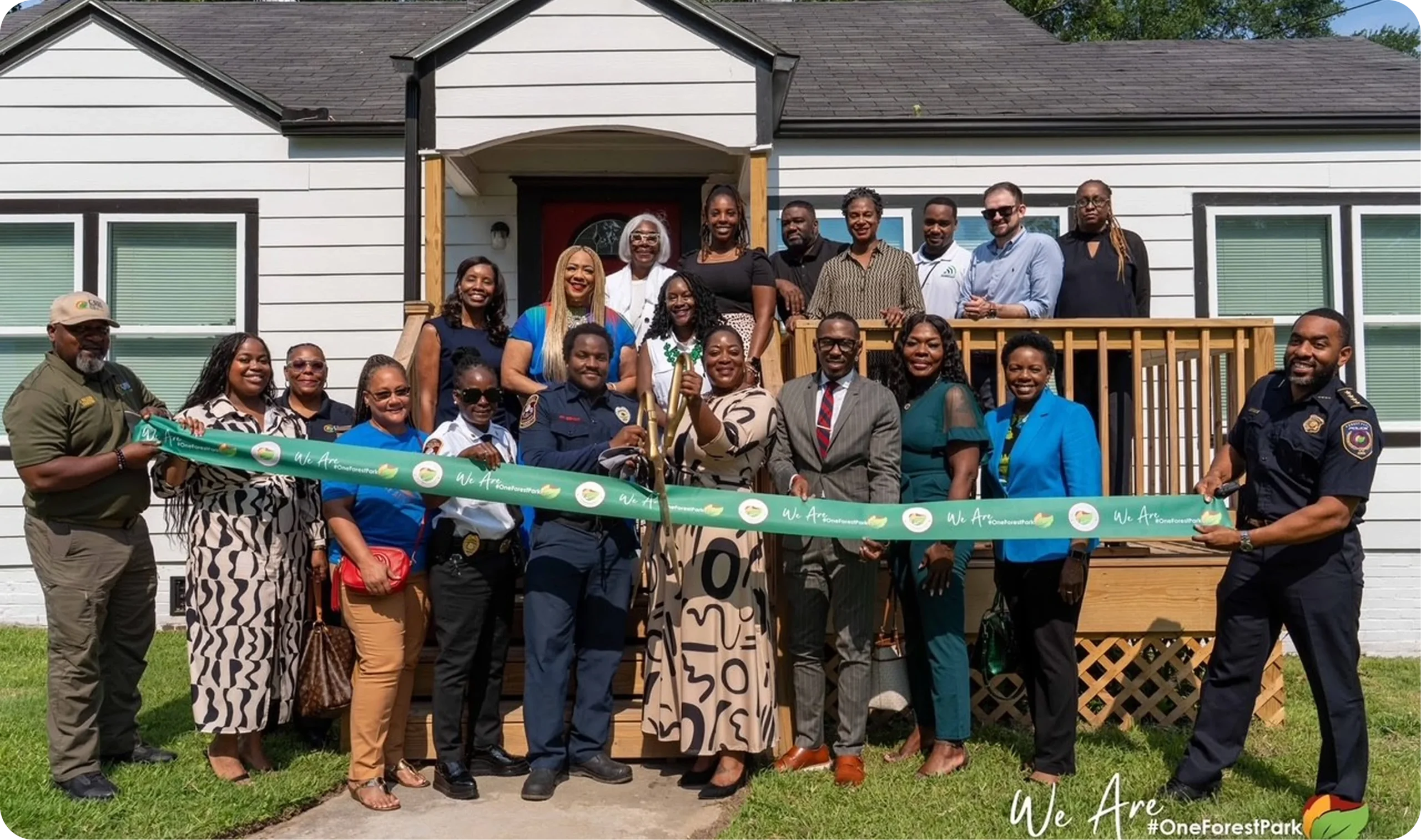 Community leaders and officials holding a ribbon-cutting ceremony outside a renovated house.