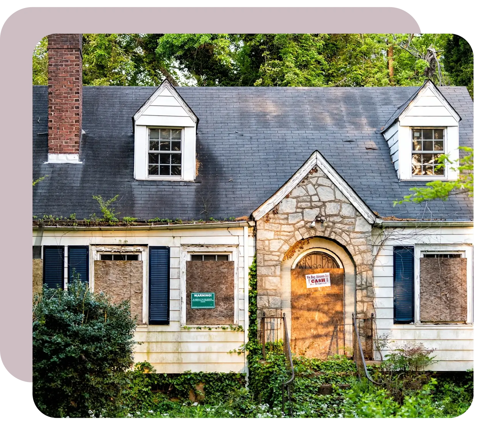 An abandoned residential house with boarded-up windows and overgrown vegetation.