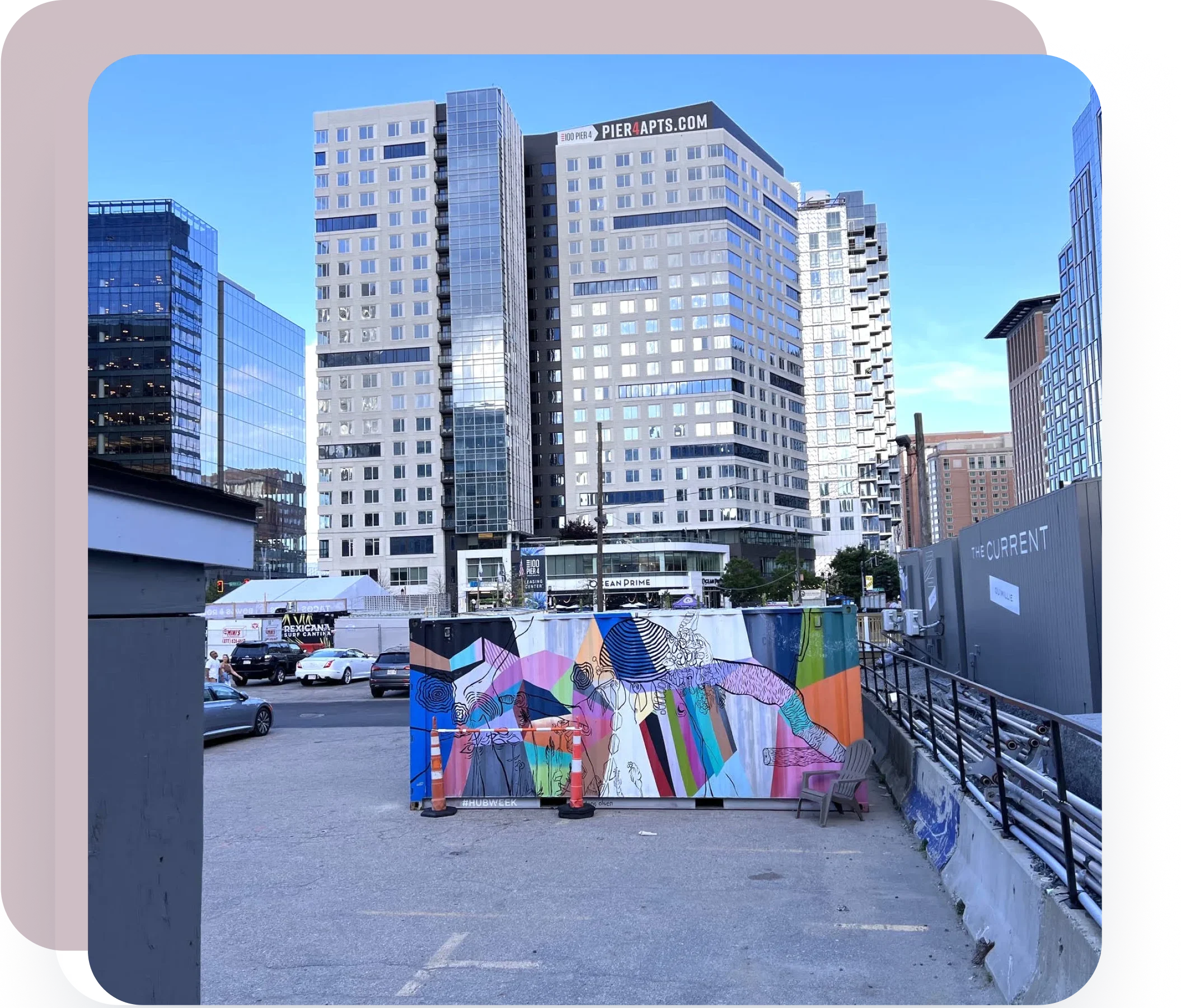 Vibrant urban public space with colorful artwork mural and high-rise city buildings in the background.